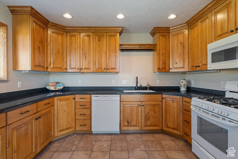 Kitchen featuring white appliances, a sink, brown cabinets, and recessed lighting
