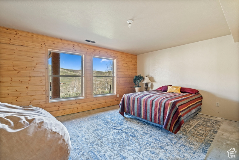 Bedroom with wood walls and concrete flooring