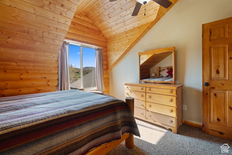 Bedroom with wood ceiling, vaulted ceiling, carpet flooring, a ceiling fan, and log walls