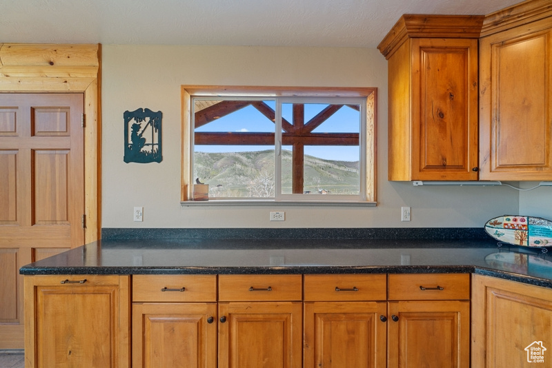 Kitchen with brown cabinetry and dark stone counters
