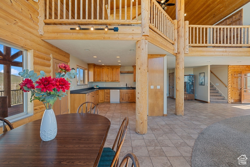 Dining room with stairs, a towering ceiling, log walls, and recessed lighting