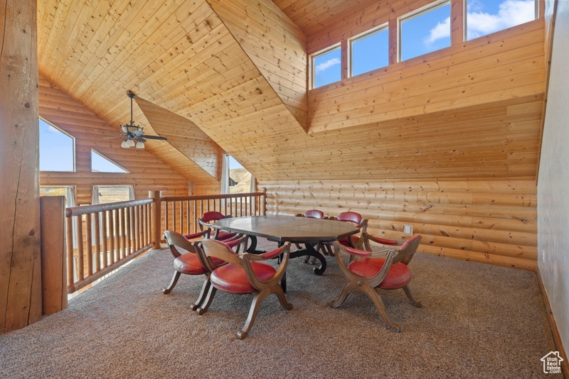 Dining area featuring wood ceiling, rustic walls, a ceiling fan, high vaulted ceiling, and carpet floors