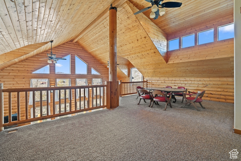 Rec room featuring a ceiling fan, rustic walls, high vaulted ceiling, plenty of natural light, and wooden ceiling with exposed beams