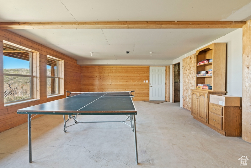 Game room featuring unfinished concrete floors and wooden walls