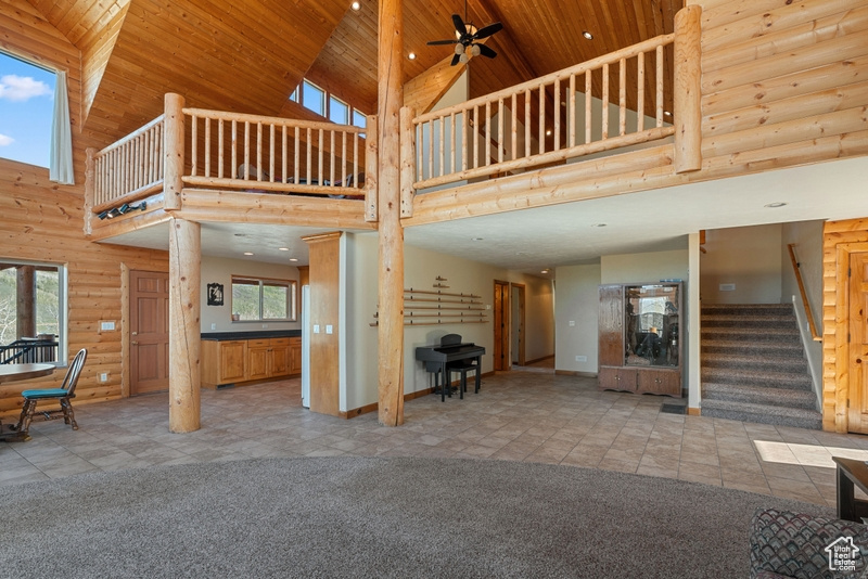 Unfurnished living room with high vaulted ceiling, stairway, carpet, wooden ceiling, and baseboards