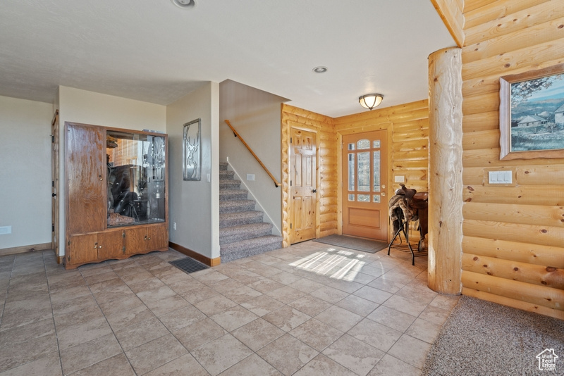 Entryway featuring baseboards, stairs, and rustic walls