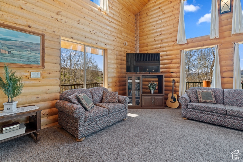 Carpeted living room with log walls and high vaulted ceiling
