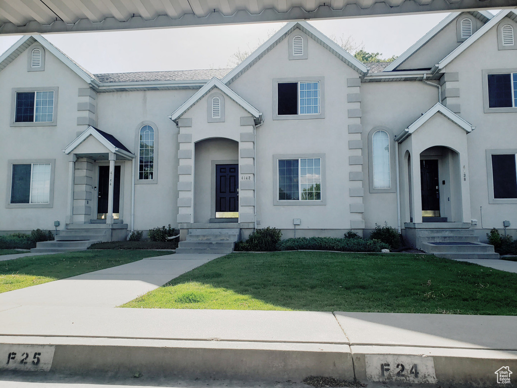 View of front facade with a front yard and stucco siding