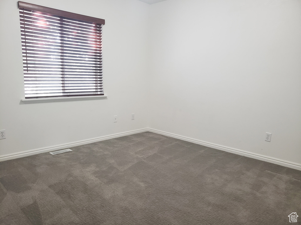 Empty room with dark colored carpet and baseboards