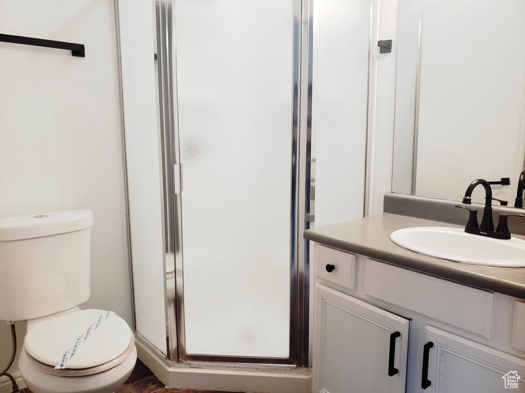 Full bath featuring a shower stall, vanity, and toilet