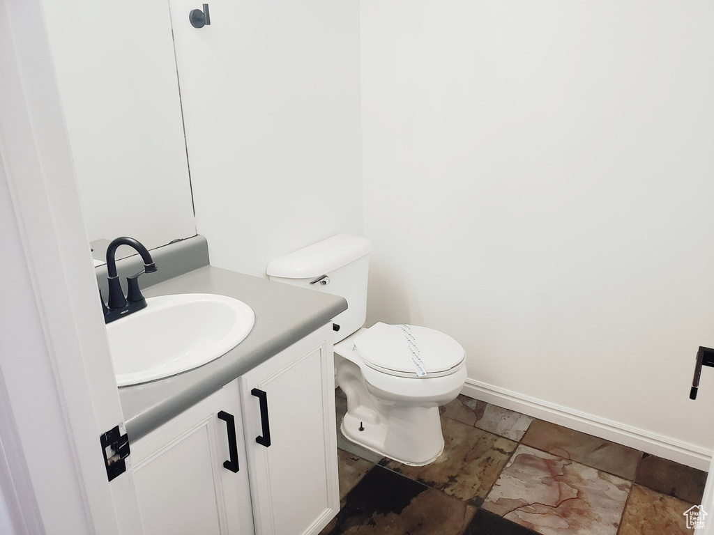 Bathroom with vanity, toilet, and baseboards