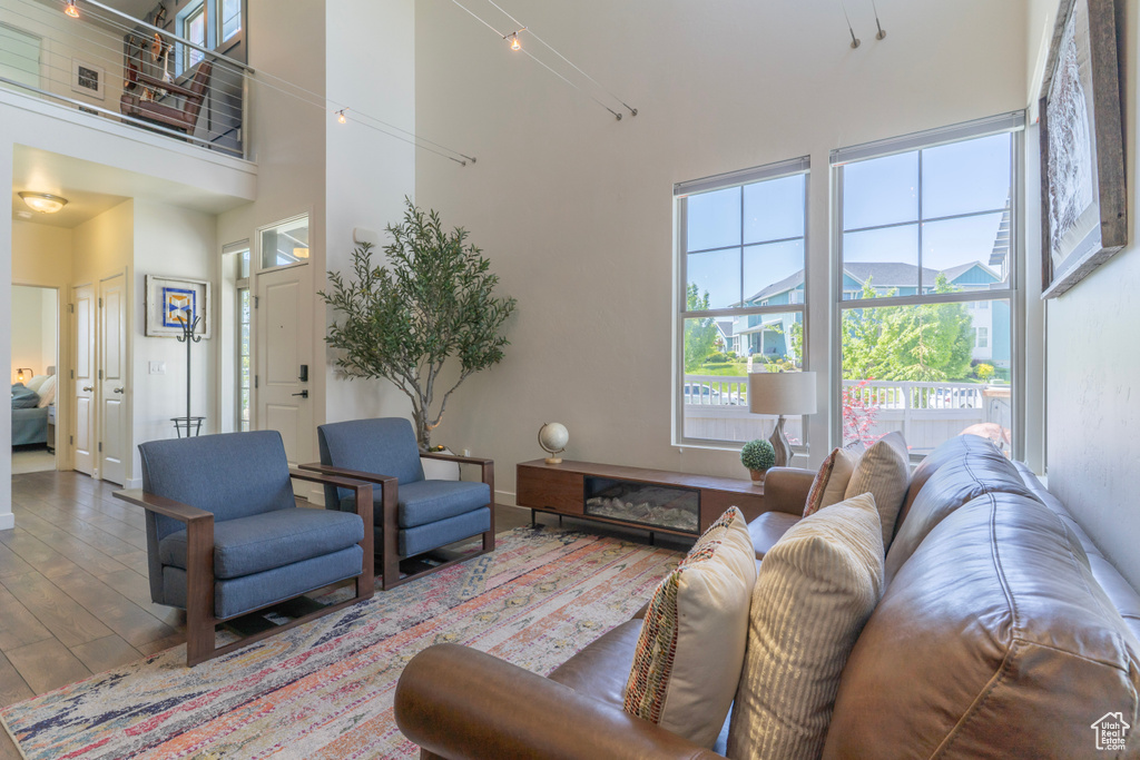 Living room with a high ceiling, wood finished floors, and baseboards