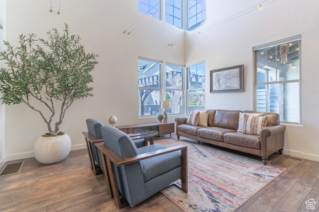 Living area with hardwood / wood-style flooring, baseboards, and a high ceiling