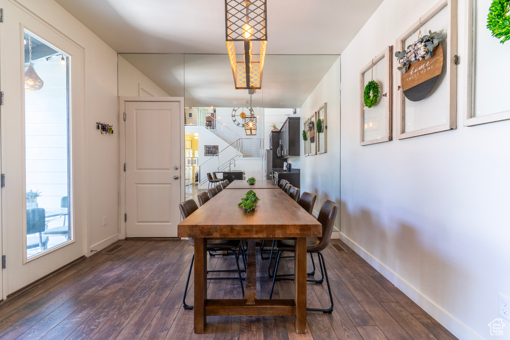 Dining space with dark wood finished floors, stairway, baseboards, and a chandelier