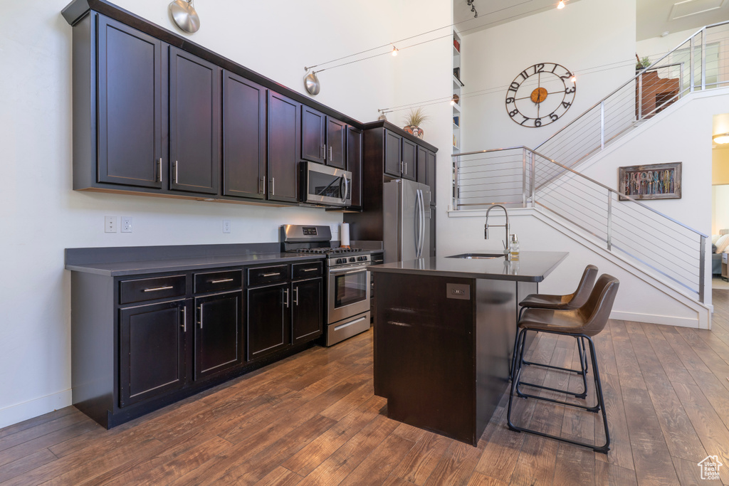 Kitchen featuring appliances with stainless steel finishes, dark countertops, a sink, and baseboards