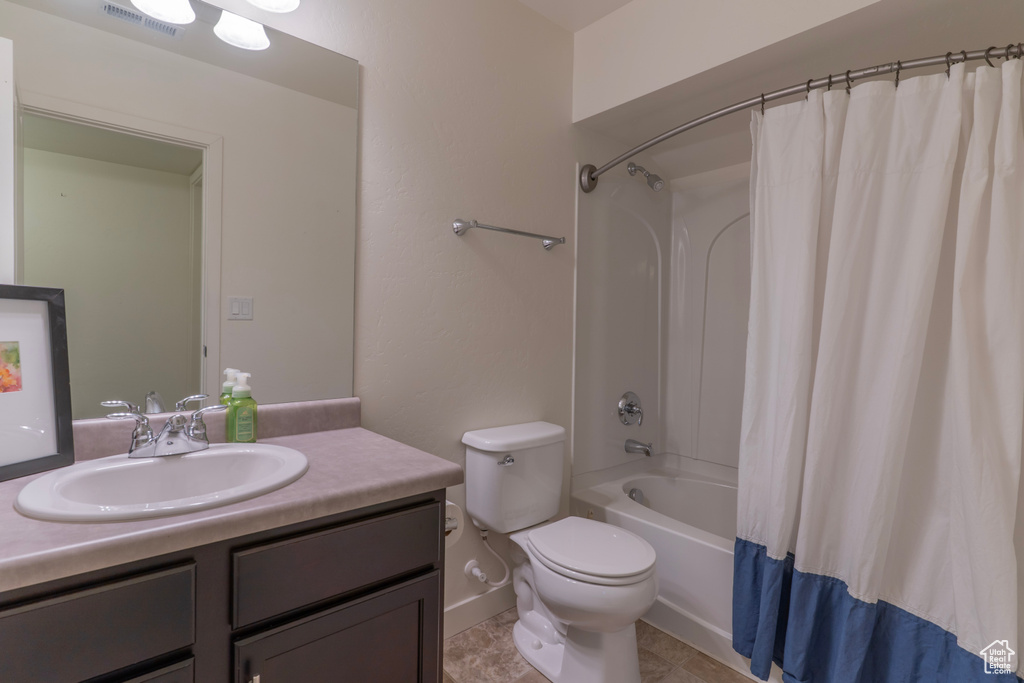Full bath featuring vanity, toilet, shower / tub combo with curtain, and baseboards