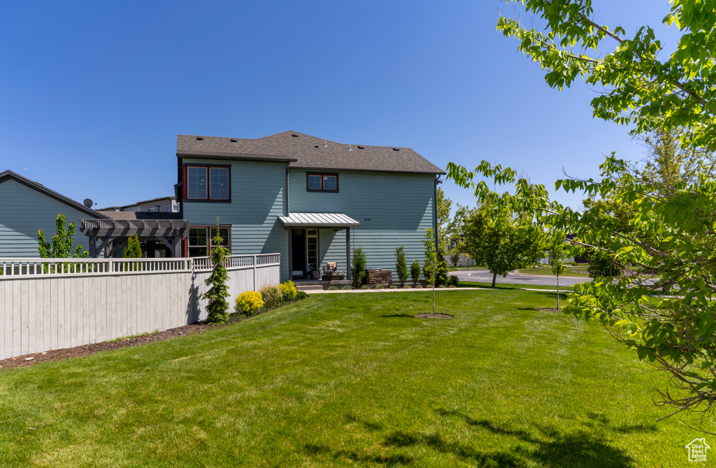Rear view of house with a lawn and a pergola