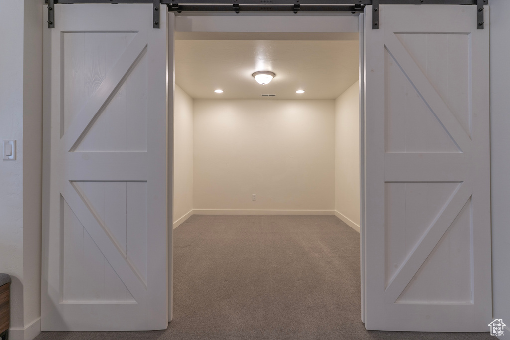 Basement with a barn door, carpet, baseboards, and recessed lighting