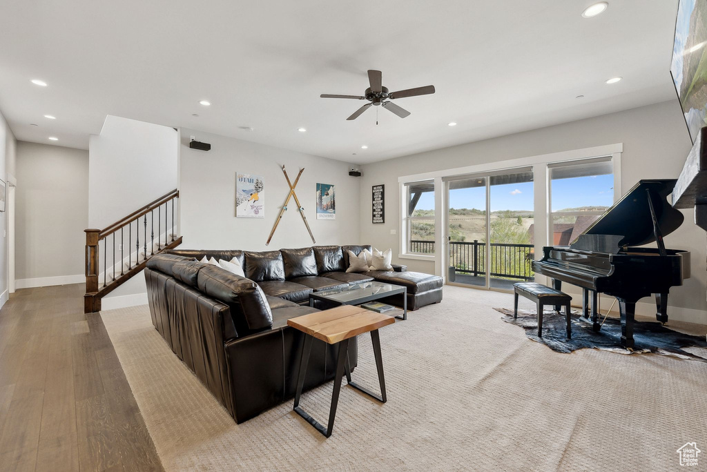 Living area with recessed lighting, ceiling fan, baseboards, stairs, and light wood finished floors