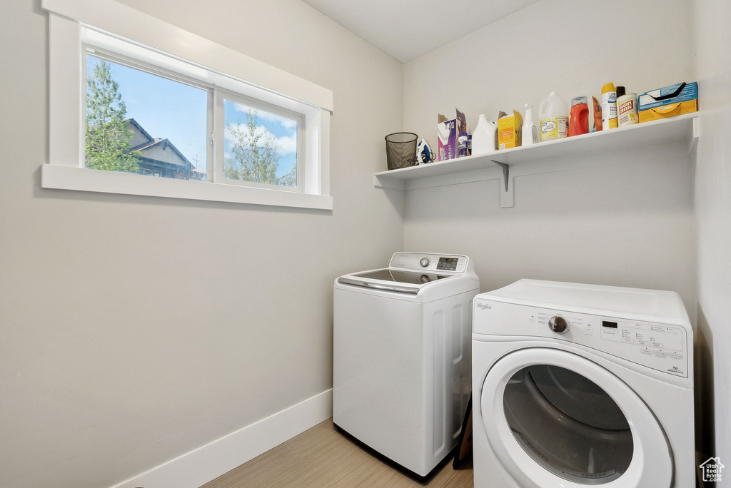 Laundry area featuring washer and clothes dryer, healthy amount of natural light, baseboards, and light wood finished floors
