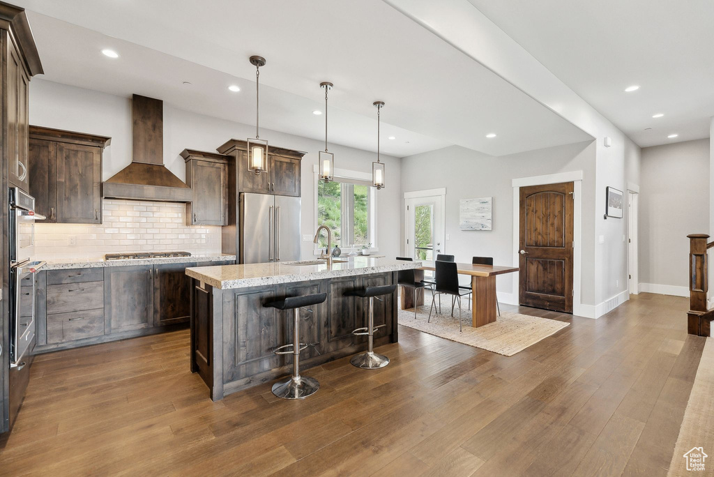 Kitchen with premium range hood, appliances with stainless steel finishes, a sink, dark wood finished floors, and recessed lighting