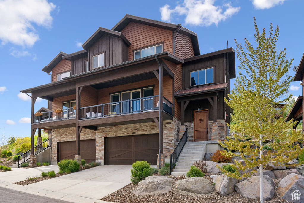 View of front facade with stone siding, stairway, board and batten siding, and concrete driveway