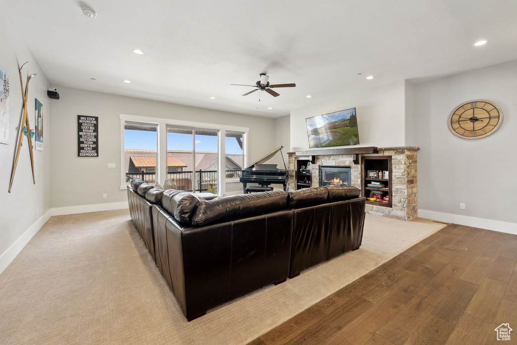 Living room with a fireplace, a ceiling fan, recessed lighting, baseboards, and light wood-type flooring