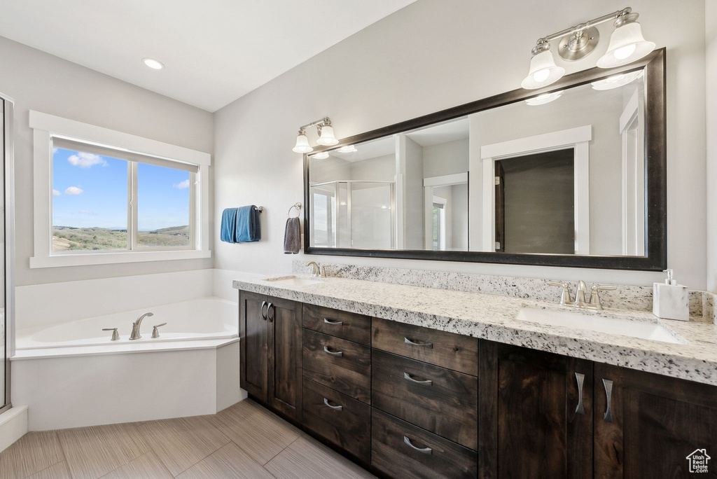 Bathroom featuring double vanity, a bath, and a stall shower