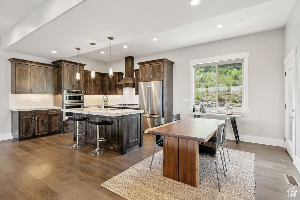 Kitchen featuring appliances with stainless steel finishes, recessed lighting, a sink, a center island with sink, and backsplash