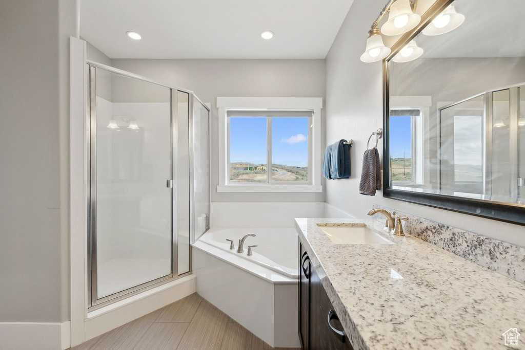 Full bathroom featuring healthy amount of natural light, a shower stall, vanity, and a bath