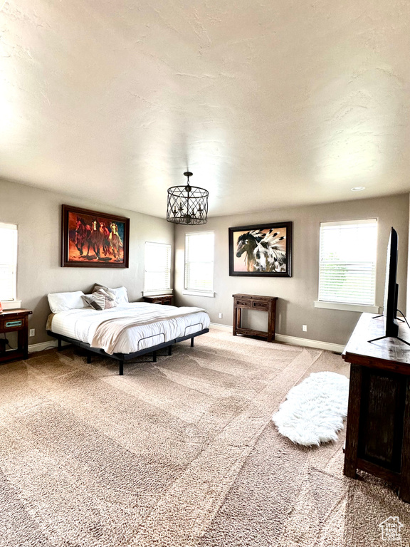 Bedroom featuring carpet, baseboards, and a chandelier