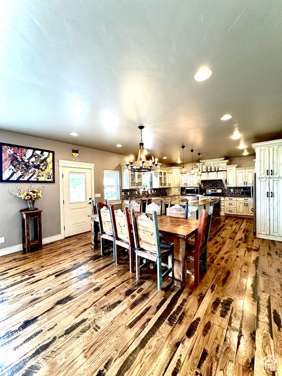 Dining area with wood-type flooring, a chandelier, recessed lighting, and baseboards