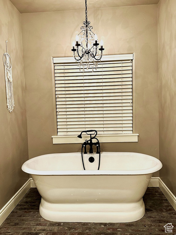 Bathroom with wood finished floors, a chandelier, baseboards, and a soaking tub