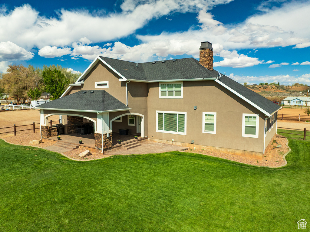 Back of house with a chimney, roof with shingles, stucco siding, a patio, and stone siding