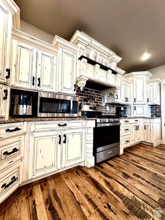 Kitchen featuring appliances with stainless steel finishes, cream cabinets, decorative backsplash, dark wood finished floors, and recessed lighting