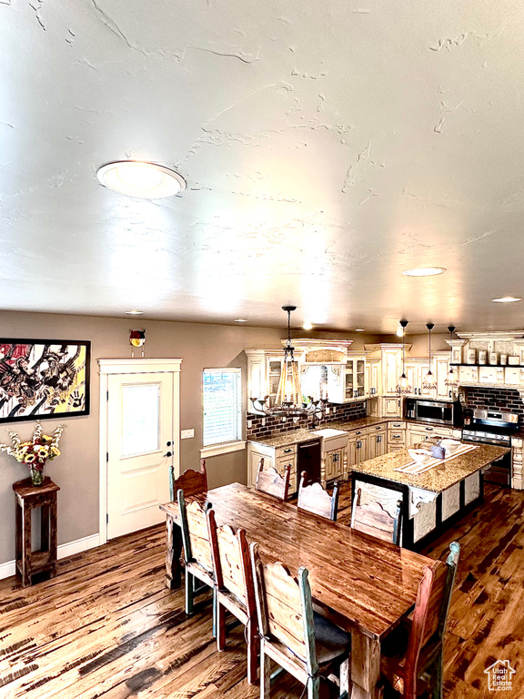 Dining room with wood finished floors, a chandelier, and baseboards