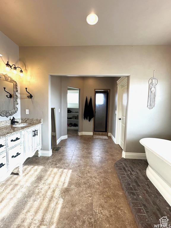 Full bath with a freestanding bath, vanity, and baseboards