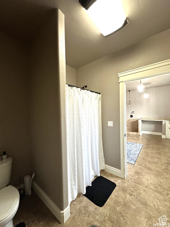 Full bathroom featuring toilet, baseboards, and curtained shower