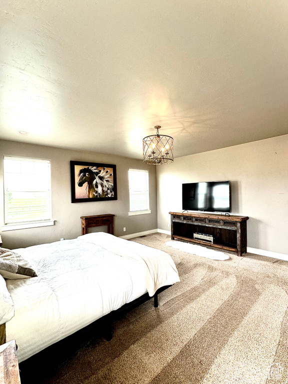 Carpeted bedroom with baseboards and a chandelier