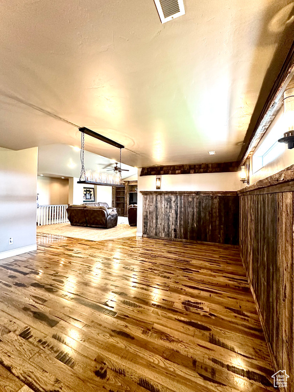 Unfurnished living room featuring ceiling fan, hardwood / wood-style flooring, vaulted ceiling, and a fireplace