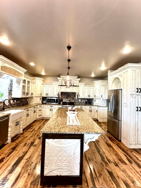 Kitchen with stainless steel appliances, dark wood-type flooring, a sink, backsplash, and recessed lighting