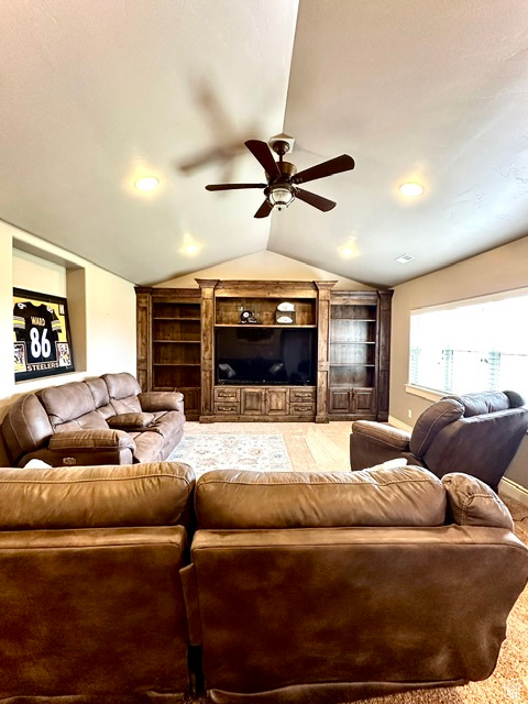 Carpeted living room with ceiling fan, vaulted ceiling, baseboards, built in features, and recessed lighting