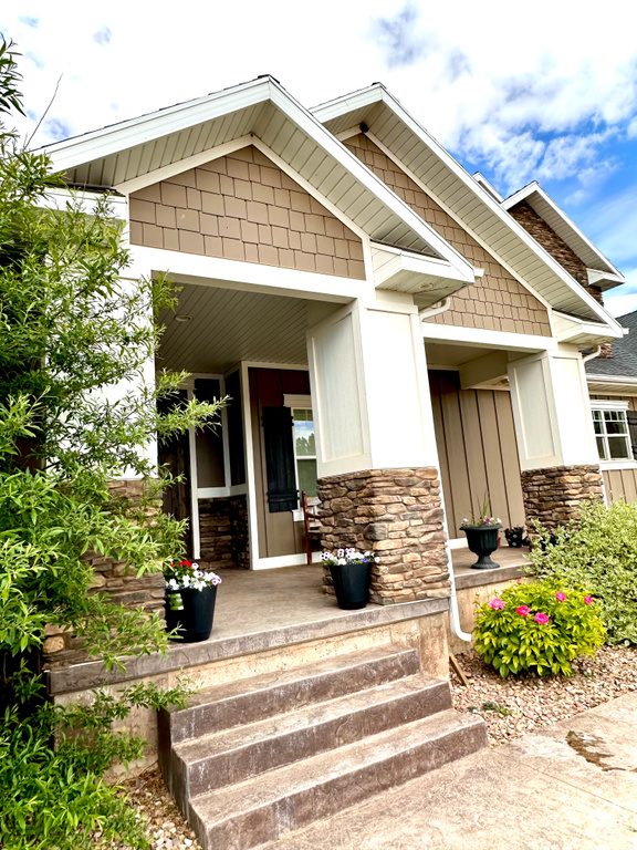 View of exterior entry with a porch and stone siding