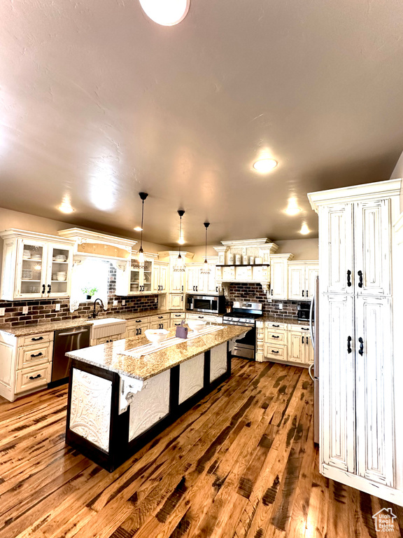 Kitchen featuring stainless steel appliances, tasteful backsplash, a kitchen bar, a kitchen island, and dark wood-style floors