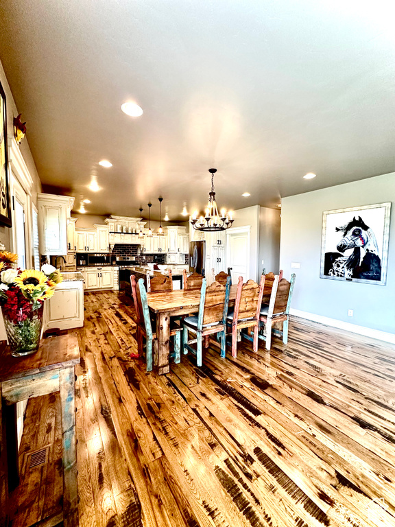 Dining room featuring a chandelier, light wood-style floors, recessed lighting, and baseboards