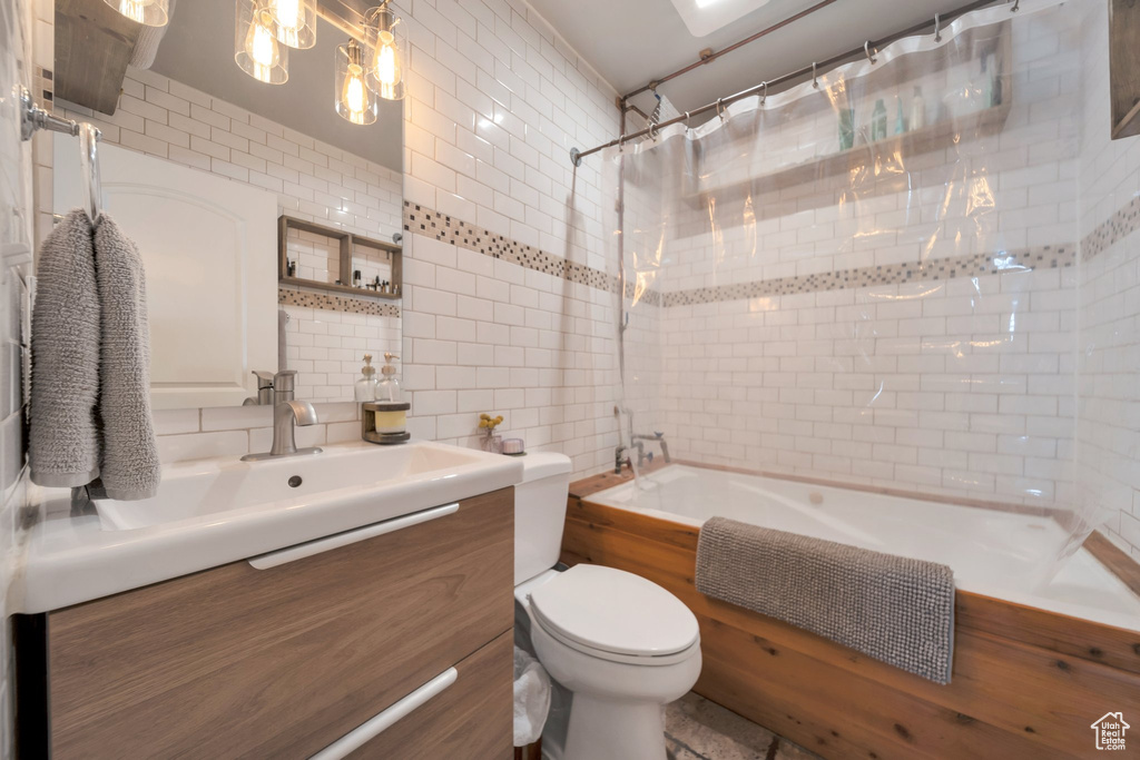Bathroom with tile walls, vanity, shower / tub combo with curtain, toilet, and backsplash