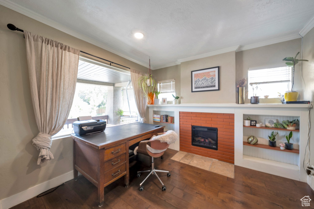 Office space with crown molding, wood-type flooring, a brick fireplace, baseboards, and recessed lighting