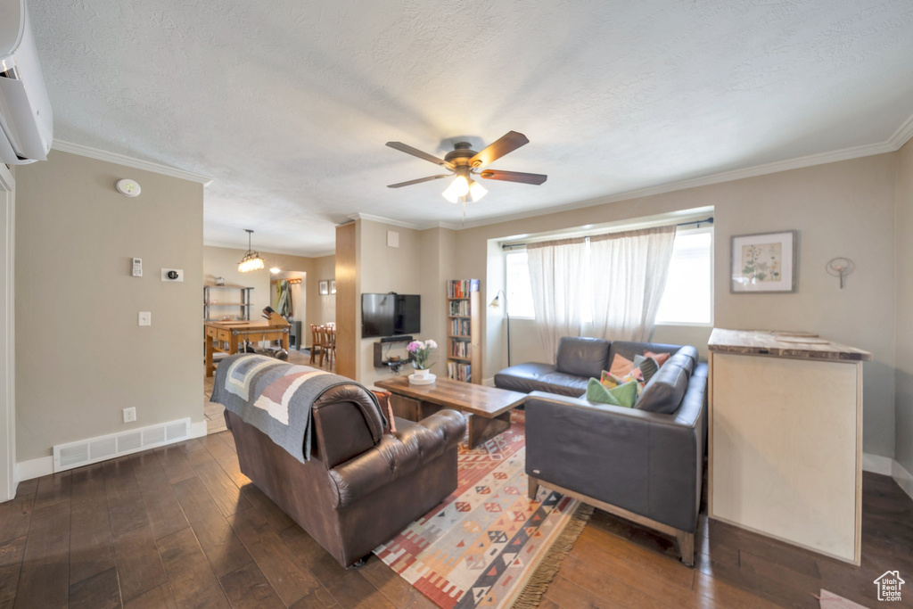 Living room with dark wood-type flooring, baseboards, ceiling fan, crown molding, and an AC wall unit