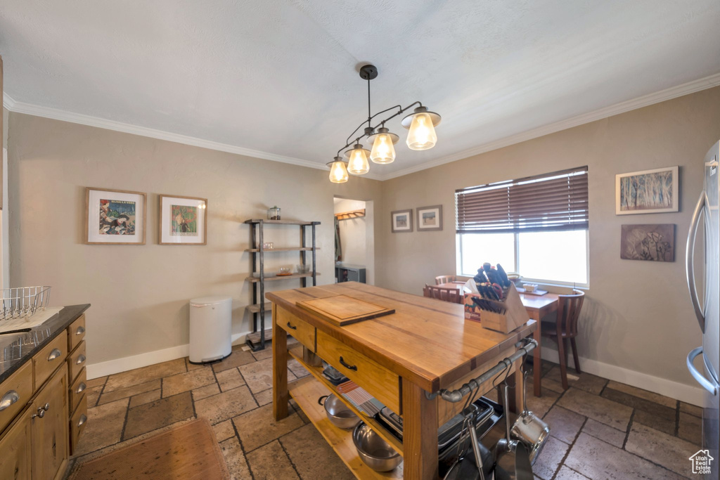 Dining area with stone tile floors, ornamental molding, and baseboards
