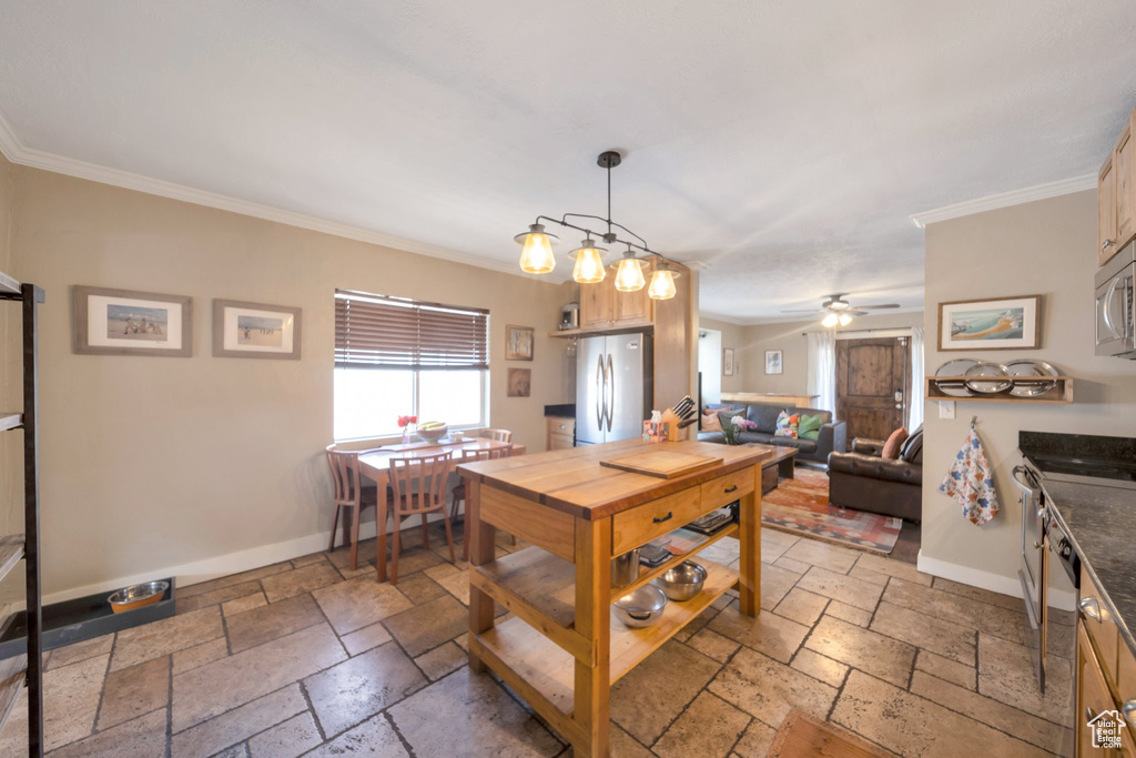 Kitchen featuring stainless steel appliances, stone tile flooring, baseboards, and crown molding